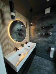 Modern bathroom renovation with backlit round mirror and floating vanity